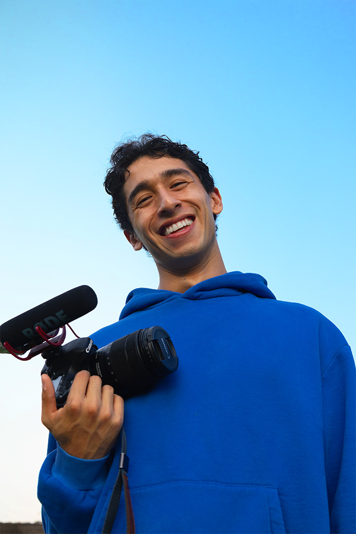 Josh Juar smiling while holding a camera and microphone